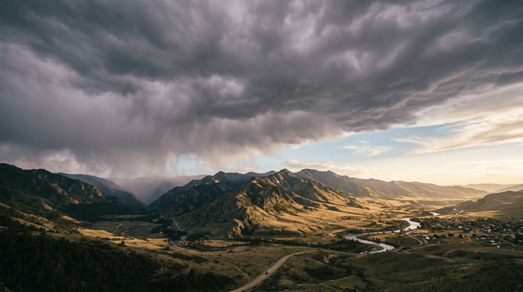 Mountain valley with winding river beneath dramatic storm clouds