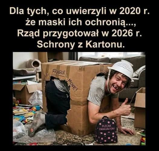 Mężczyzna siedzący w kartonowym pudełku, uśmiechający się i pokazujący kciuk w górę, otoczony zabawkami. Na ścianie tekst odnoszący się do masek i schronów z kartonu.